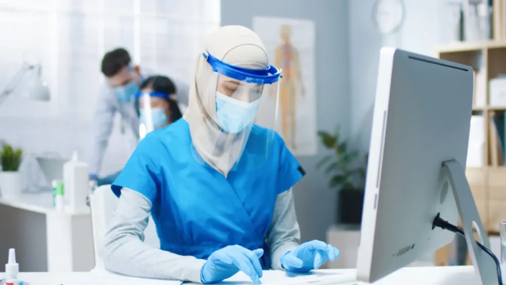 سكرتارية طبيب تجلس أمام جهاز كمبيوتر وتستخدمه