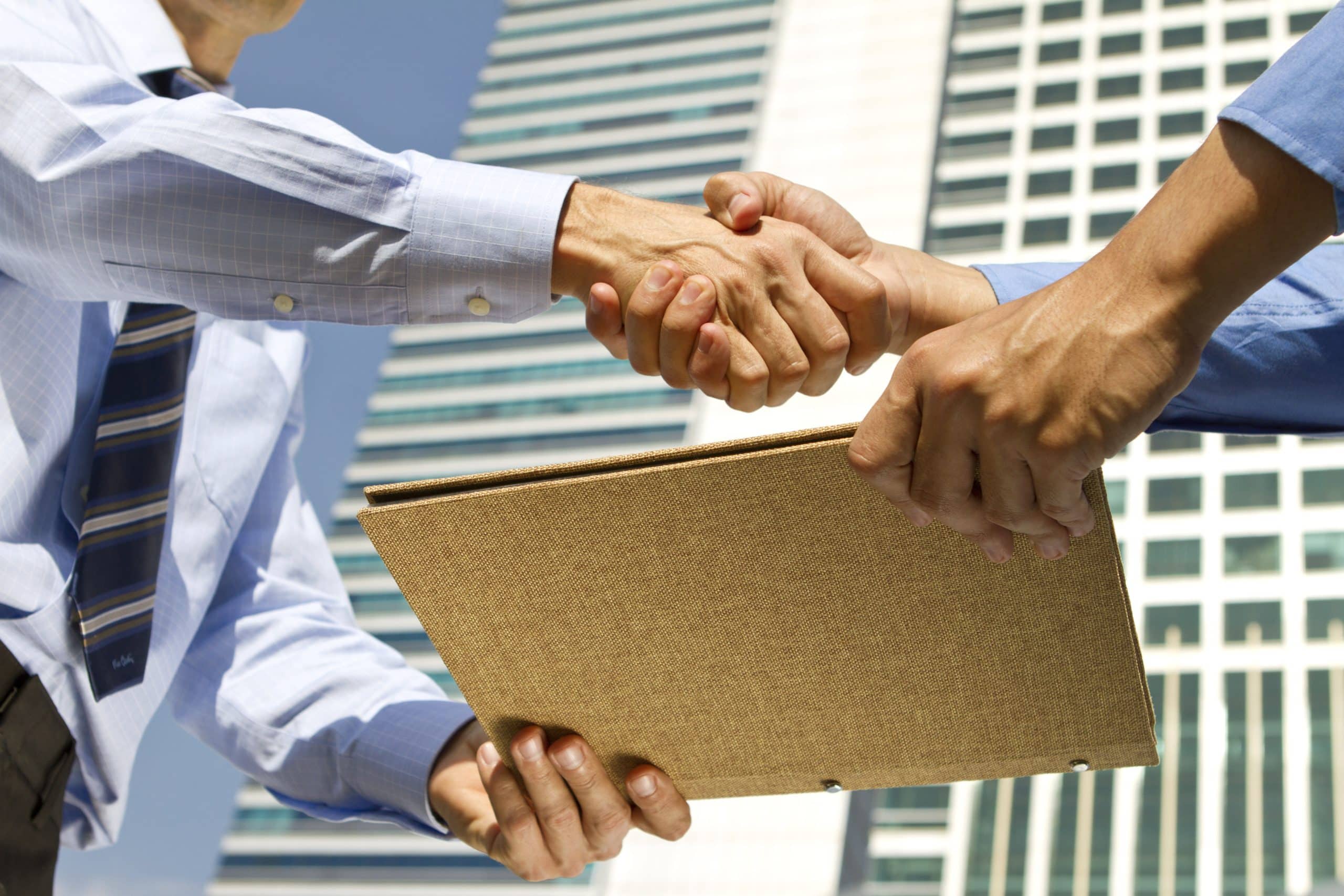 Two businessmen, of Asian and Caucasian descent, shake hand over their deal.